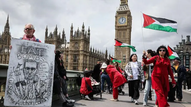 一名抗议者展示了一幅讽刺英国首相基尔·斯塔默的画，画中他站在威斯敏斯特桥上，站在伊丽莎白塔前，读着“让他们吃炸弹”的字样。