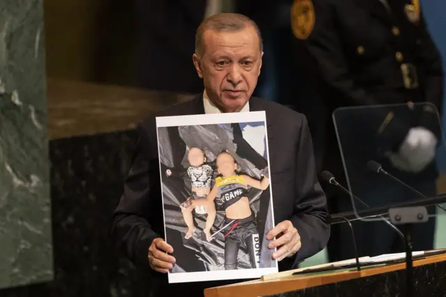 Recep Tayyip Erdogan, Madaxweynaha Jamhuuriyadda Turkiga oo sita Sawirka Carruur Qaxooti Suuriyaan ah oo doonayay inay gaaraan Galbeedka Yurub.