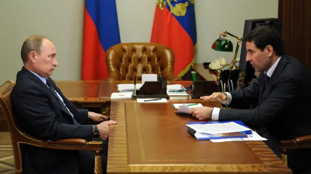 Двое мужчин сидят за столом в начальственном кабинете