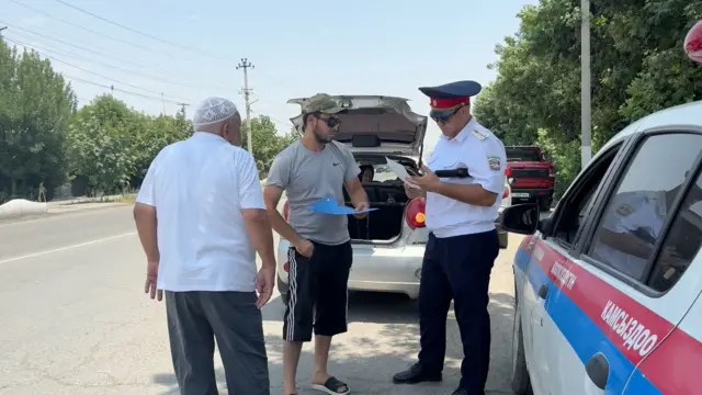 ЖКККББнын өкүлү таксисттин лицензиясын текшерип жатат