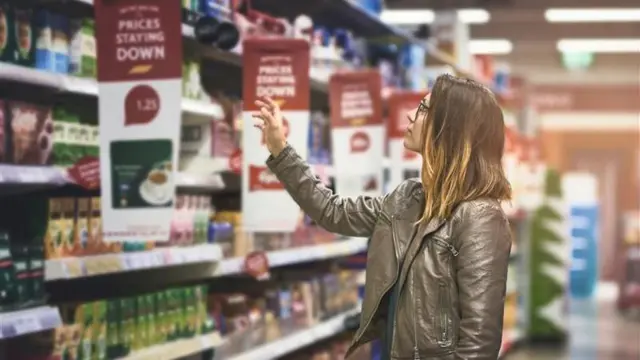 Woman wearing brown leather jacket reaching up to a shelf in a supermarket