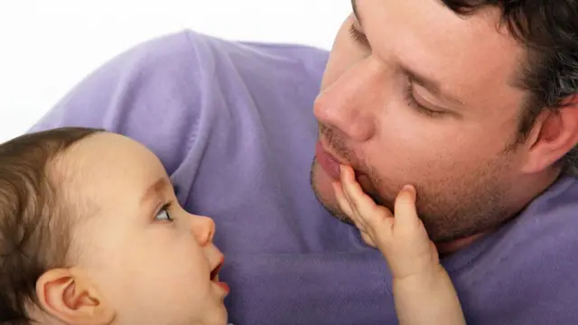 طفل يداعب رجل ويضيع يده على وجهه