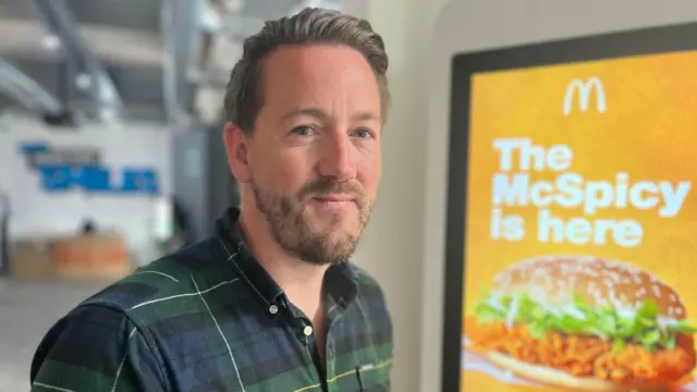 Dean Ward standing in front of a McDonald's self-service terminal