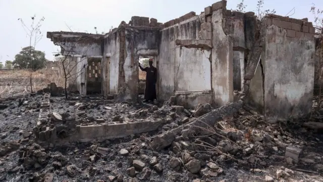 Ọkan lara awọn ile ti Boko Haram kọlu ree, o ti jona raurau. Ẹnikan duro lẹnu ọna rẹ, o di ogiri mu o si n wo orere.