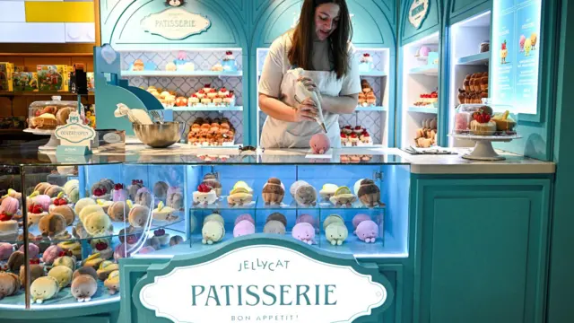 Dziewczyna przygotowuje pluszaki Jellycat w kształcie wypieków, prezentowane jak w tradycyjnej cukierni w Galeries Lafayette Haussmann w Paryżu.