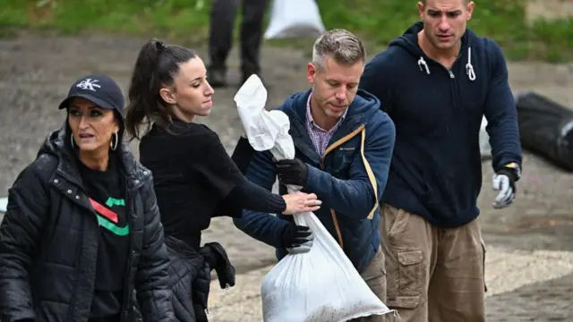 Местные жители, в том числе лидер оппозиции и член Европейского парламента Петер Мадьяр (второй справа в синей куртке), а также сторонники его партии «Тиса», помогают готовить мешки с песком для защиты от наводнения в деревне Сигетмоностор 16 сентября 2024 года