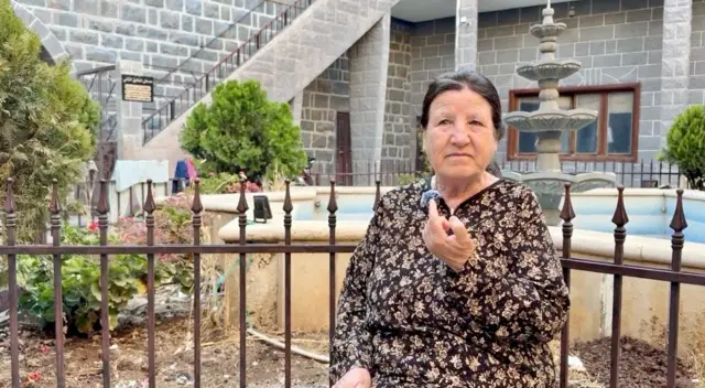 امرأة مسنة جالسة في باحة دارها تتحدث إلى مراسلة بي بي سي نيوز عربي.