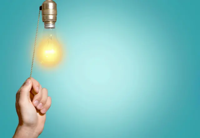 Mão de alguém acendendo uma lâmpada