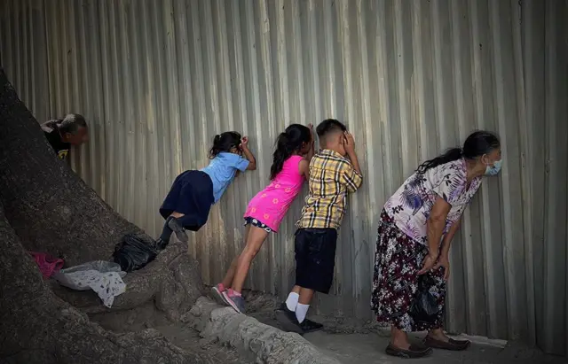 Beberapa kerabat didorong untuk mencoba melihat sekilas orang yang mereka cintai melalui lubang di dinding penjara, seperti di sini di penjara Ilopango di San Salvador.