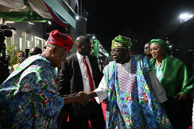 Aarẹ Bola Tinubu wọ aṣọ agbada APC, o n bọ igbakeji rẹ lọwọ. Iyawo rẹ Remi Tinubu ati ọkunrin to wọ aṣọ dudu wa lẹyin rẹ.