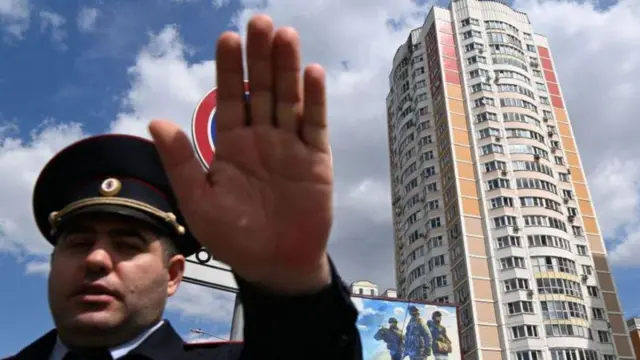 Um policialjj sporting betfrente a um dos prédios afetados pelos ataquesjj sporting betdrones