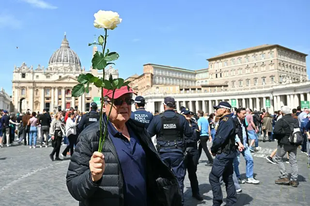 Wani mutum riƙe da fure tsaye a dandalin St Peter da ke Vatican yana alhinin rasuwar Fafaroma Francis a yau Litinin 21 ga watan Afurilun 2025