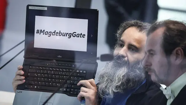 Обвиняемый из Саудовской Аравии Талеб Джавад аль-Абдулмохсен (слева) держит ноутбук с надписью «#MagdeburgGate», сидя рядом со своим адвокатом Томасом Рутковски во временном зале суда 10 ноября 2025 года.