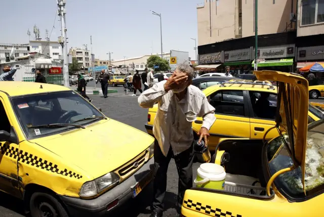 عکس آرشیوی از تابستان سال گذشته - یک راننده تاکسی در تهران خود را خنک می‌کند