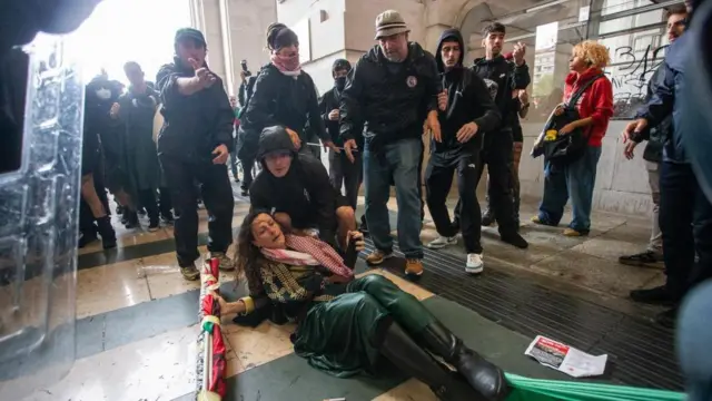 muškarac pokušava da podigne ženu koja je pala tokom protesta