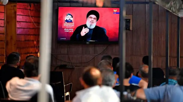 Des personnes regardent le secrétaire général du Hezbollah, Hassan Nasrallah, prononcer un discours télévisé dans un café de la banlieue sud de Beyrouth, au Liban, le 25 août 2024.