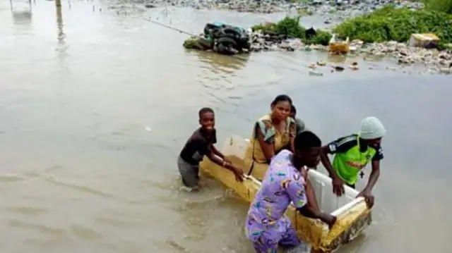 Eeyan marun to fi mọ ọmọde kan wa ni aarin agbami omi nla, obinrin kan ninu wọn joko sinu ike nla kan to wa lori omi nigba ti awọn mẹrin yoku n ti ike naa lọ siwaju