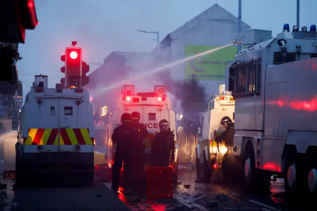 Полицийские, полицейские машины и водомет.