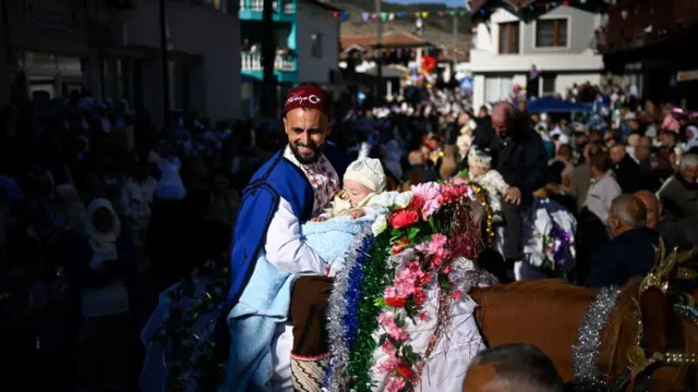 أب يحضن طفله على ظهر خيل مزينة خلال حفل ختان جماعي في بلغاريا