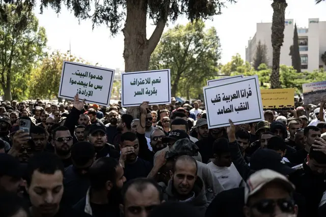 مجموعة كبيرة من البدو يرفعون لافتات كُتب عليها "قُرانا العربية قلب النقب الصامد" و "نعم للاعتراف بقرية السر" و "هدموا البيت بس ما بيهدموا الإرادة"، وذلك في إطار تظاهرة لآلاف البدو أمام "هيئة تنمية واستيطان بدو النقب" في مدينة بئر السبع، احتجاجاً على سياسات الهدم التي تنتهجها الحكومة الإسرائيلية ضد العرب. 29 مايو/أيار 2025.