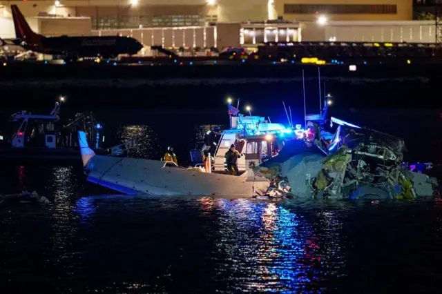 Petugas tanggap darurat memeriksa badan pesawat American Airlines yang jatuh ke Sungai Potomac, Washington DC, Amerika Serikat,  Kamis (30/01).