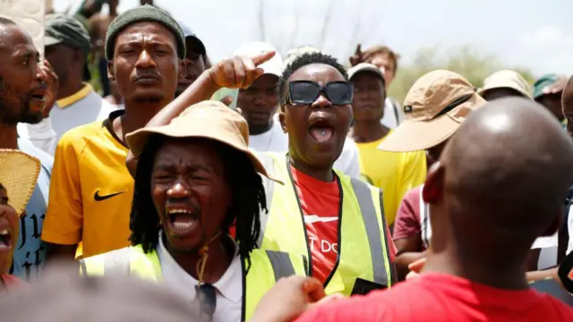 Des membres de la communauté protestent à l'entrée de la mine alors qu'une opération de sauvetage est en cours pour récupérer les mineurs illégaux de la mine de Stilfontein.