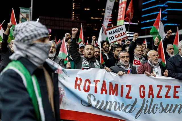 onlarca kişi protesto ediyor, önde "rotamız gazze" yazan bir pankart var. 