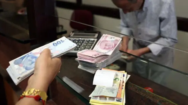 A customer buys US dollars in exchange for Turkish lira at an exchange office in Ankara on July 20, 2023.