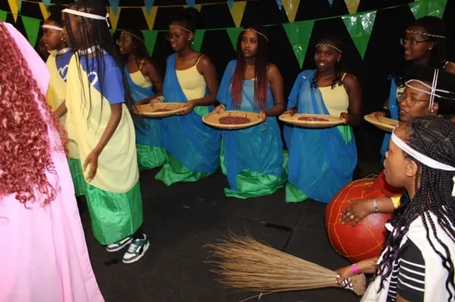 Abakobwa bakiri bato mu mwambaro w'imvutano bafashe intaro mu maboko 