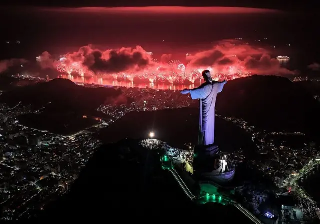 Un espectáculo de fuegos artificiales anarajados con el monumento del Cristo Redentor en primer plano 