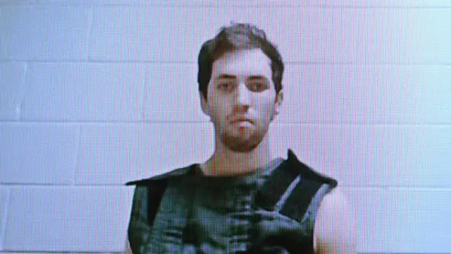 Taylor Robinson, un joven con barba, mira a la cámara un computador.