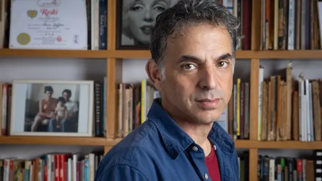 O escritor Etgar Keret com estantejogos de aposta com bonus gratislivros atrás dele emjogos de aposta com bonus gratiscasa