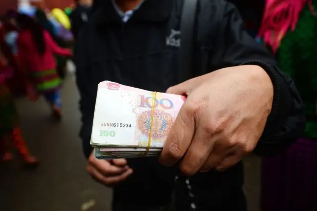 Bức ảnh chụp ngày 28/20/2018 cho thấy một người cầm tiền Nhân dân tệ của Trung Quốc tại chợ Chủ nhật ở Mèo Vạc, một huyện miền núi biên giới của tỉnh Hà Giang, nơi có nhiều cô dâu bị bán sang Trung Quốc