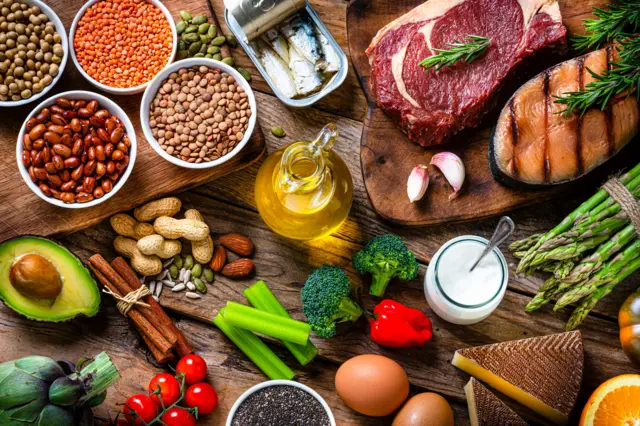 protein içeren sağlıklı besinleri gösteren bir fotoğraf, içinde baklagiller, peynir, yumurta, et ve yemişler var. 