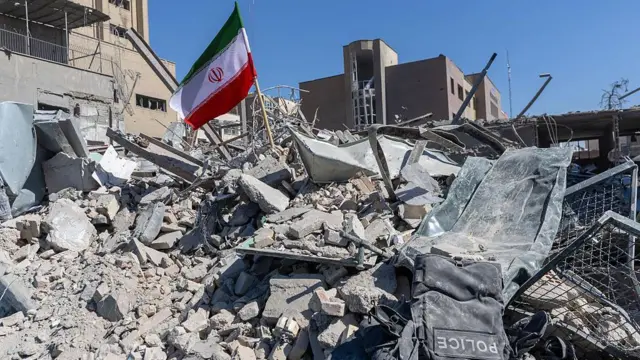 3 Mart 2026'da Tahran'da, hava saldırılarında hasar gören bir polis karakolunun enkazına İran bayrağı dikildi.
