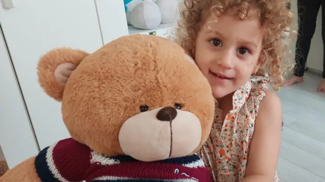 A photo of Delsa, aged 3, hugging a large teddy bear