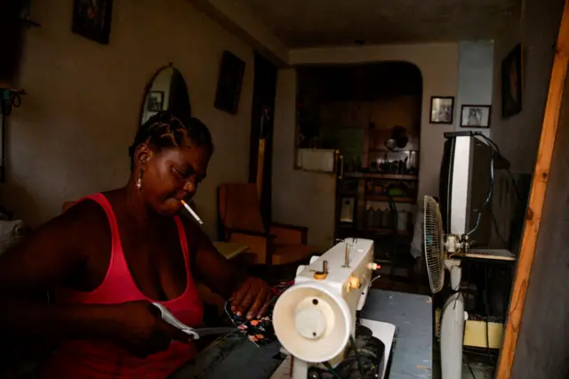 Una costurera espera a que vuelva la luz para seguir con su trabajo este viernes en La Habana.