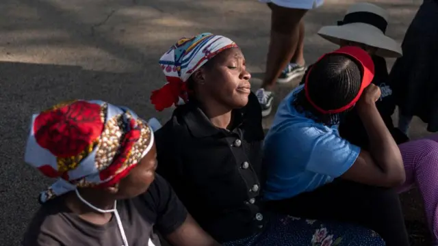 Des femmes attendent à la surface de la mine Buffelsfontein à Stilfontein, l'air fatigué.