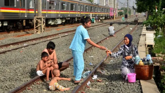 Sebuah keluarga yang tinggal di pinggir rel kereta api membeli jamu di Bekasi, Jawa Barat pada 3 April 2020, sebagai upaya pencegahan virus corona COVID-19.