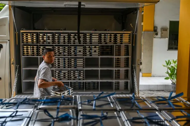 Seorang anggota staf memuat piring makan siang pada hari pertama program makan gratis di sekolah menengah Muhammadiyah di Sidoarjo pada 6 Januari 2025. Indonesia meluncurkan program makanan gratis senilai Rp335 triliun yang ambisius pada 6 Januari untuk memerangi pertumbuhan terhambat akibat kekurangan gizi, janji pemilihan utama Presiden Prabowo Subianto.
