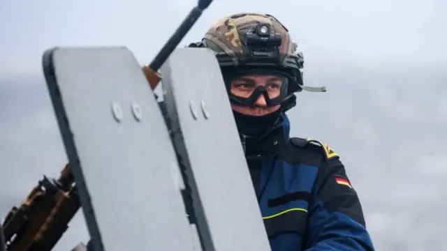 یک سرباز که صورتش پوشیده همراه با یک تیربار