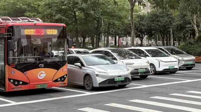 EVであることを示す緑色のナンバープレートを付けたバスと4台の車が、広州市茘枝区の横断歩道で停車している