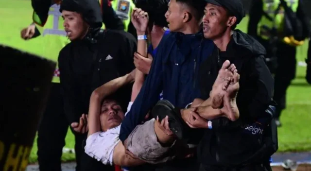 Dalam foto yang diambil pada 1 Oktober 2022 ini, sejumlah suporter Arema FC menggotong korban yang tak sadarkan diri di Stadion Kanjuruhan.