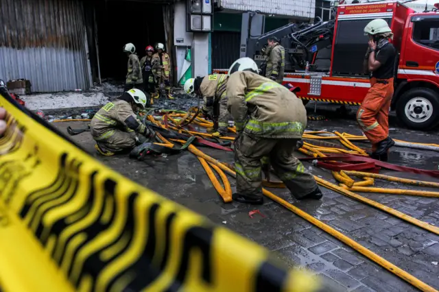 Petugas pemadam kebakaran merapihkan selang air usai memadamkan api di perkantoran Terra Drone di jalan Letjen Soeprapto, Cempaka Baru, Kemayoran, Jakarta, Selasa (9/12).