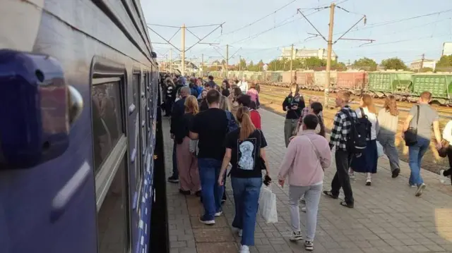 Натовп йде пероном біля потяга