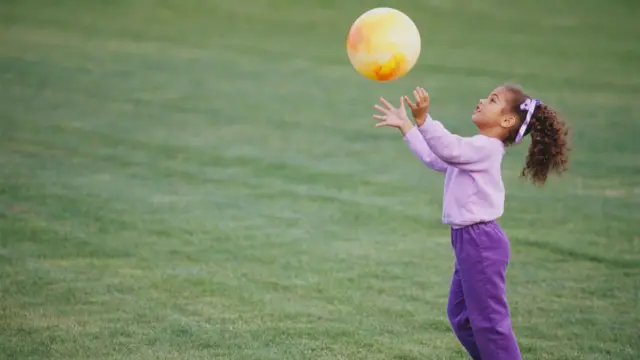 Niña atrapando una pelota. 