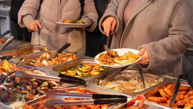Двоє людей набирають їжу в ресторані типу шведського столу