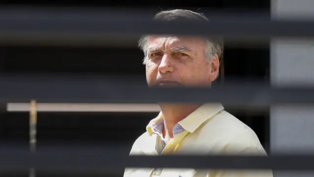 Žair Bolsonaro u žutoj košulji gleda kroz rešetke ka kameri