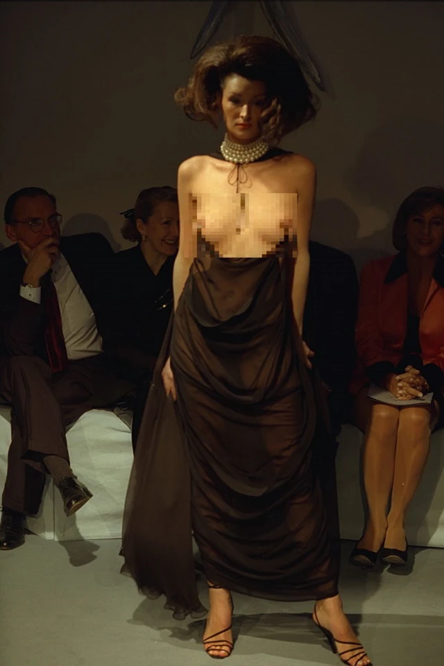 Чорна напівпрозора сукня, що звисає із сосків моделі, соски заблюрені