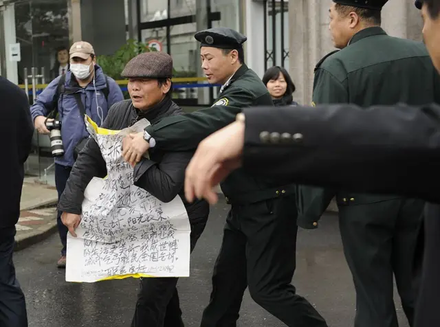 2012年2月22日，在上海浦東新區人民法院外，一名上訪者（中）被一名保全人員推開。中國國家副主席習近平在最近一次訪美期間表示，中國將採取實際措施改善人權狀況，但他同時承認「人權狀況總有改進的空間」。 